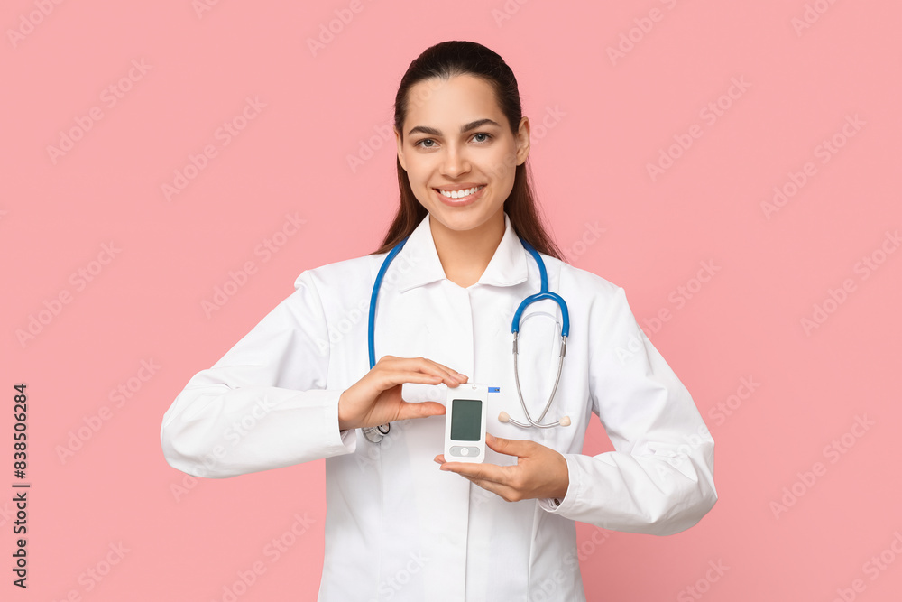 Portrait of female doctor with portable glucose meter on pink background Portrait of female doctor with portable glucose meter on pink background