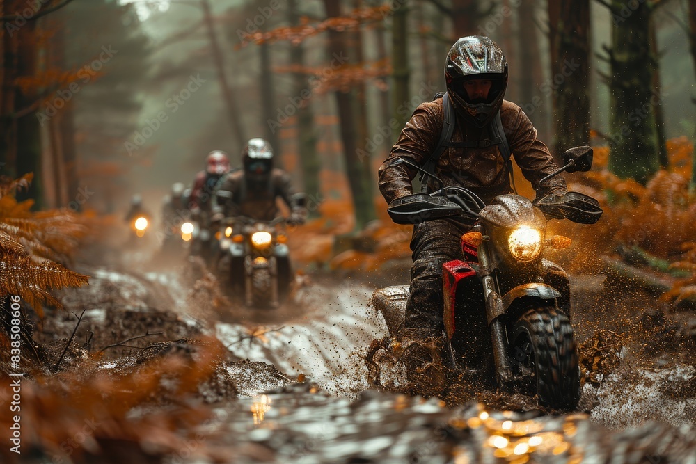 A group of motorcyclists ride across a wet forest ground, spraying mud as they maneuver A group of motorcyclists ride across a wet forest ground, spraying mud as they maneuver
