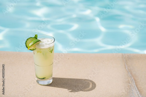 Color photo of a mint mojito sitting on the side of a pool, dramatic shadow - summer resort vacation