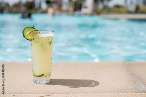 Color photo of a mint mojito sitting on the side of a blue pool- summer resort vacation
