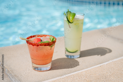 Strawberry Watermelon cocktail margarita and mint mojito next to the edge of a blue pool  