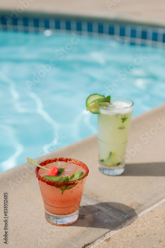 Two colorful tropical drinks on the edge of a resort pool. Color vertical photo.