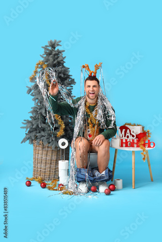 Young man sitting on toilet...