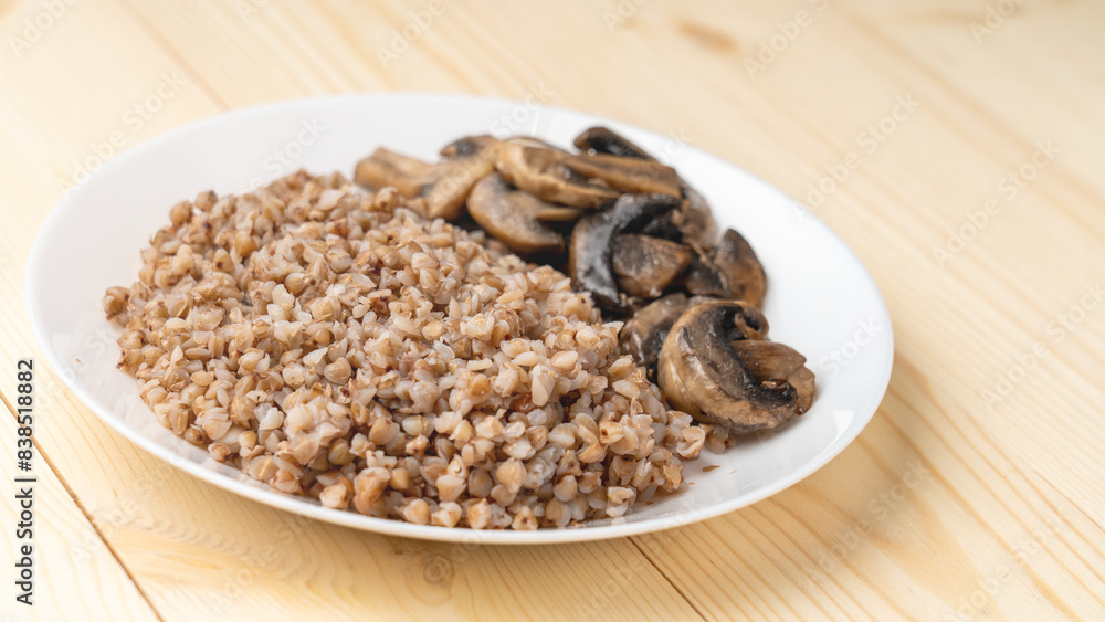 Buckwheat porridge with fried mushrooms on a plate on a wooden background. Healthy diet food. The concept of healthy eating Buckwheat porridge with fried mushrooms on a plate on a wooden background. Healthy diet food. The concept of healthy eating