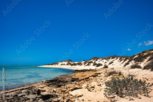Fototapeta Naklejka Na Ścianę i Meble -  Shallow coast with rocks and sand dunes at the remote coast of Cape Range National Park, Western Australia
