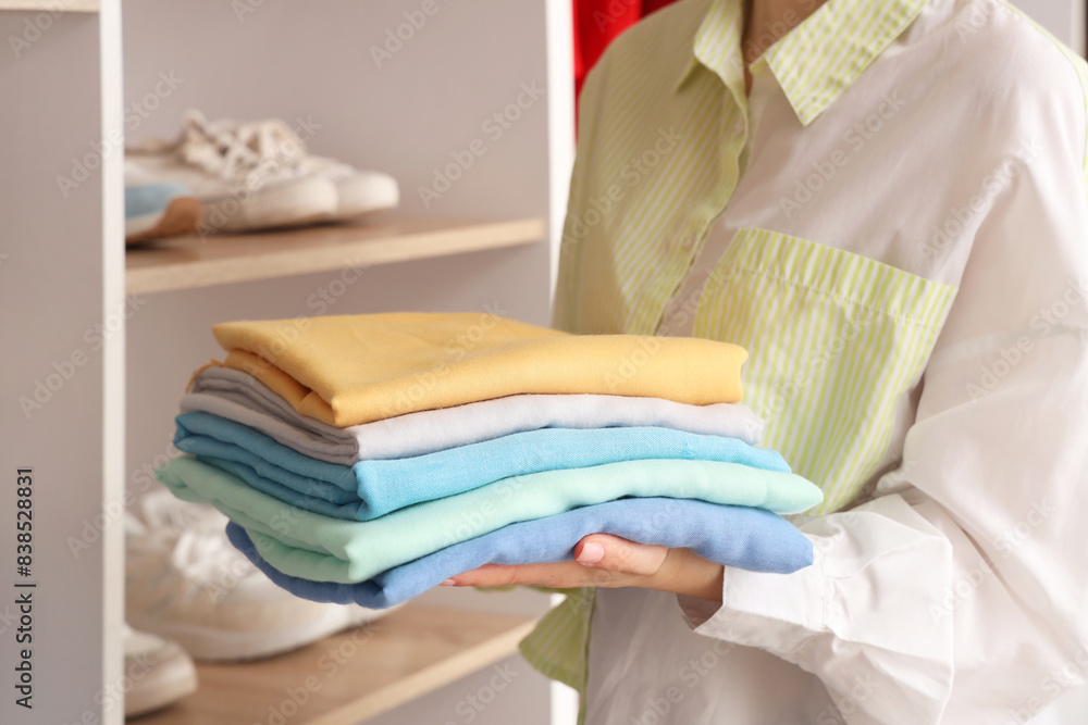 Woman with stack of clothes in wardrobe at home Woman with stack of clothes in wardrobe at home