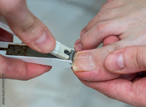 closeup of a young caucasian man in the bathroom cutting his toenails with a nail clipper