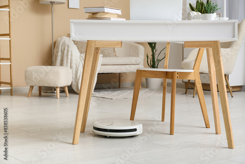 Modern robot vacuum cleaner under table at home
