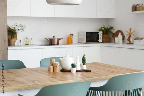 Teapot with plants and candles on dining table in kitchen