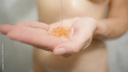 Naked Woman in the Shower pouring Orange Shower Gel into her hand. Slow motion. photo