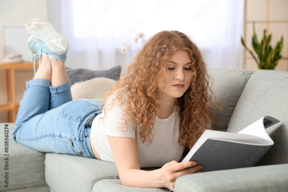 Young woman reading magazine on sofa at home Young woman reading magazine on sofa at home