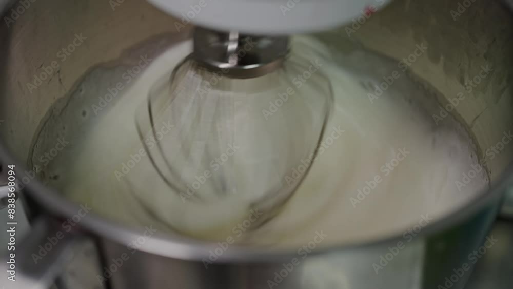 Close-up view of a metal whisk rapidly mixing cream in a machine, perfect for culinary and kitchen-themed content. Whisk Mixing Fresh Cream in a Stainless Steel Mixing Bowl Close-up view of a metal whisk rapidly mixing cream in a machine, perfect for culinary and kitchen-themed content. Whisk Mixing Fresh Cream in a Stainless Steel Mixing Bowl