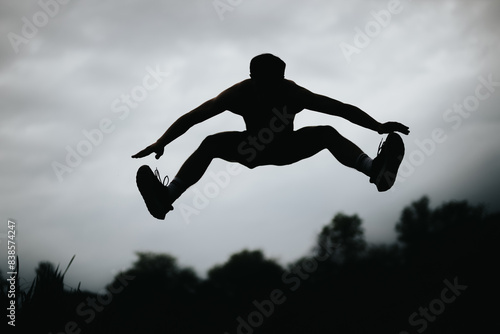 Wallpaper Mural Silhouette of a man performing high jumps in an outdoor setting under a dramatic cloudy sky. Torontodigital.ca