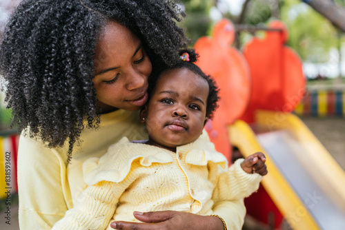 A woman is holding a baby in a yellow sweater