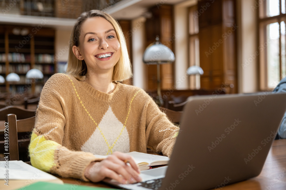 Blonde smiling woman at the laptop in the library Blonde smiling woman at the laptop in the library
