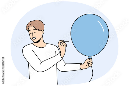 Man with balloon holds needle, wanting to make loud explosion to cheer people around. Happy guy dressed in casual style with blue balloon in hands makes prank to scare or amuse friends.