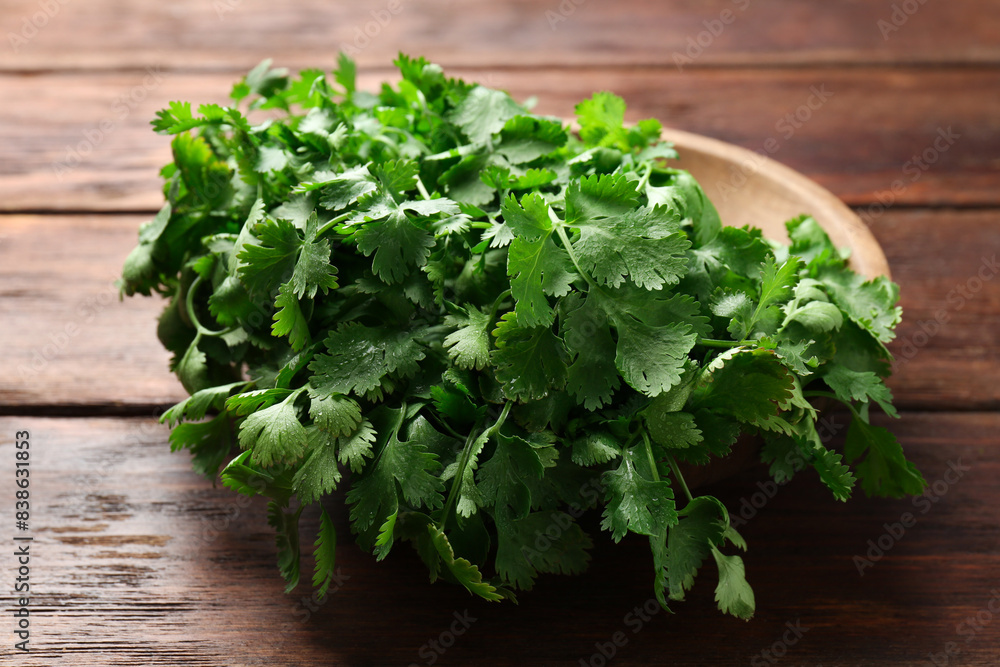 Fresh coriander in bowl on wooden table, closeup Fresh coriander in bowl on wooden table, closeup