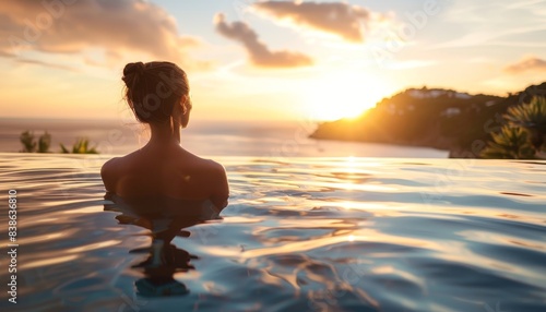 Relaxing in an infinity pool while enjoying a breathtaking sunset view over the ocean, inspiring serenity and peace. © narak0rn