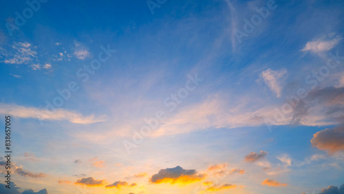 A beautiful sunset sky, transitioning from deep blue at the top to warm golden and orange hues near the horizon. Wispy clouds are scattered throughout, illuminated softly by the setting sun. 