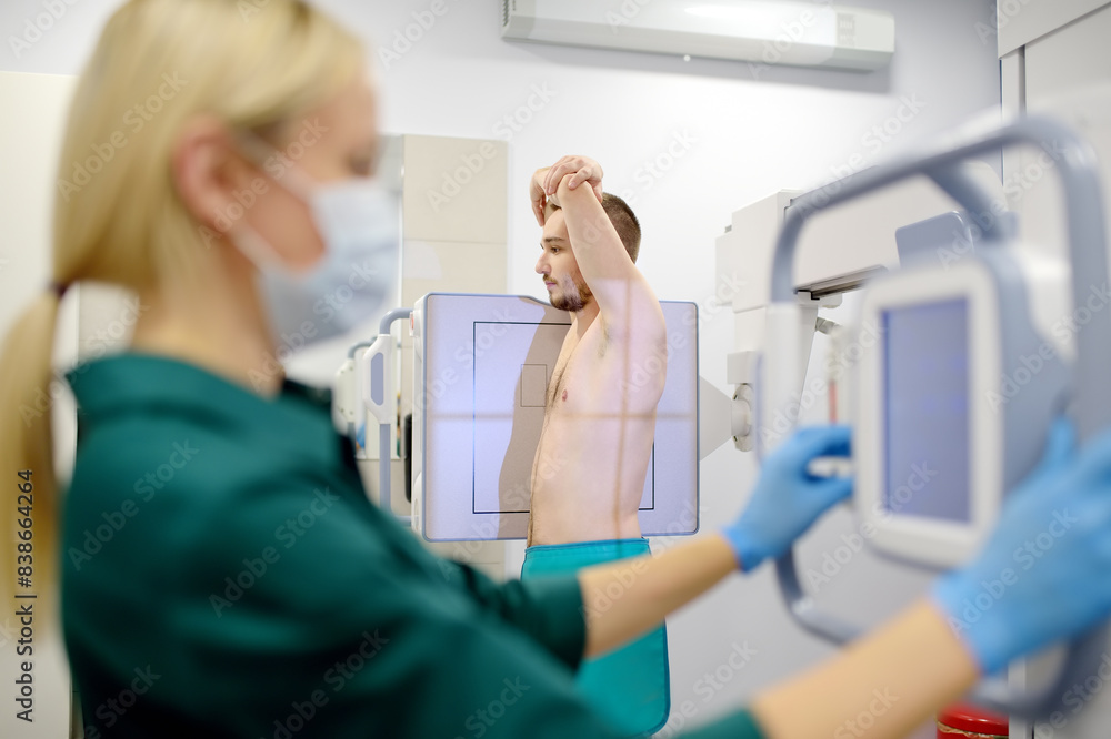Female radiologist is making an Xray of lungs of patient in X-ray room of modern clinic. Doctor performs a fluorography. Medical examination of people is prevention of tuberculosis spread Female radiologist is making an Xray of lungs of patient in X-ray room of modern clinic. Doctor performs a fluorography. Medical examination of people is prevention of tuberculosis spread