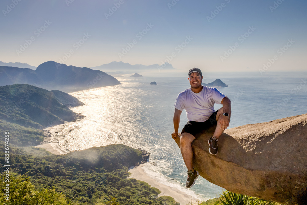 Fototapeta premium Adventurous climber hangs off Pedra do Telégrafo with breathtaking coastal view in Rio de Janeiro