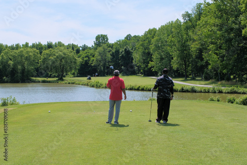 Golfers survey a hole with water hazard