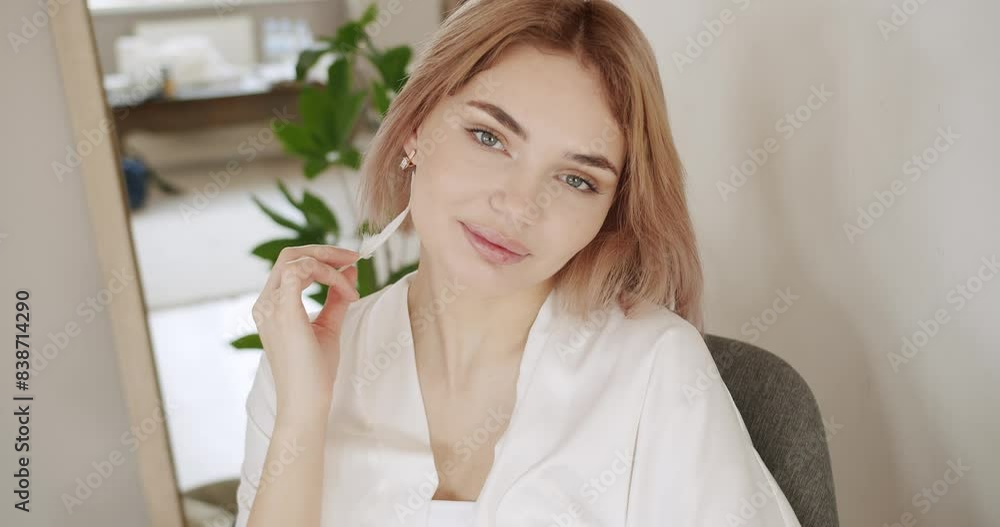 Portrait of young beautiful woman with nude makeup holding playing with feather on face. Beautiful Young Woman with Clean Fresh Skin. Skin care concept at home. Portrait of young beautiful woman with nude makeup holding playing with feather on face. Beautiful Young Woman with Clean Fresh Skin. Skin care concept at home.