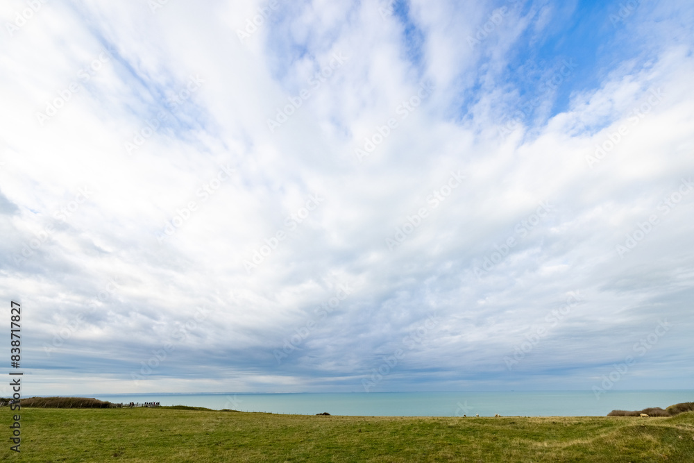 Scenic view of a wide, cloudy sky over a peaceful sea and grassy landscape in a serene, natural setting. Scenic view of a wide, cloudy sky over a peaceful sea and grassy landscape in a serene, natural setting.