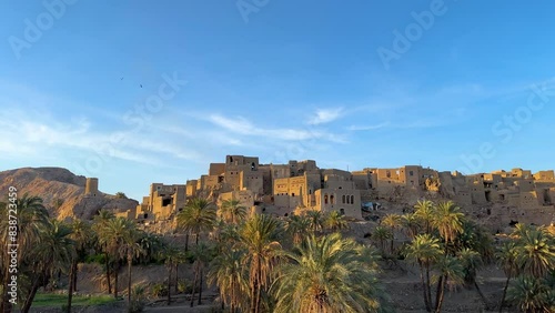 Wonderful view of Desert oasis landscape hilltop mud brick clay architecture design house building castle style in Morocco travel destination Date palm garden grove spring season blue sky rural life photo