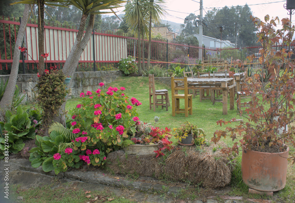 Fototapeta premium Garden with vibrant flowers and rustic wooden furniture.