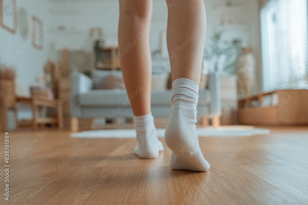 Closeup foot of young woman walking on wooden floor at home Closeup foot of young woman walking on wooden floor at home