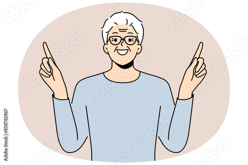 Eldery man came up with idea and points fingers up with smile to draw attention to your ad. Gray-haired pensioner in glasses recommends paying attention to good offer or cool idea.