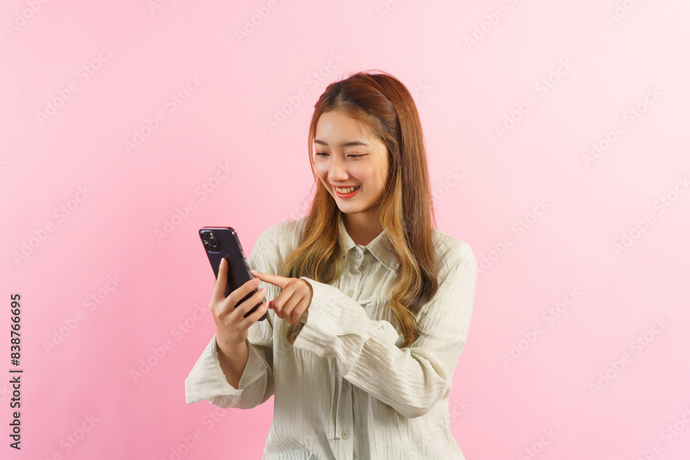 Young women touchscreen on smartphone to surfing social media isolated on pink background