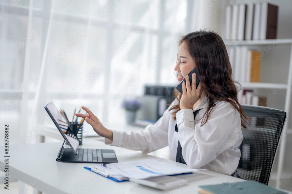 A woman is talking on her cell phone while working on a laptop A woman is talking on her cell phone while working on a laptop