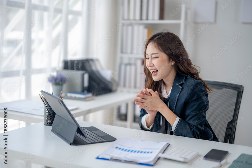 A woman is sitting at a desk with a laptop and smiling A woman is sitting at a desk with a laptop and smiling