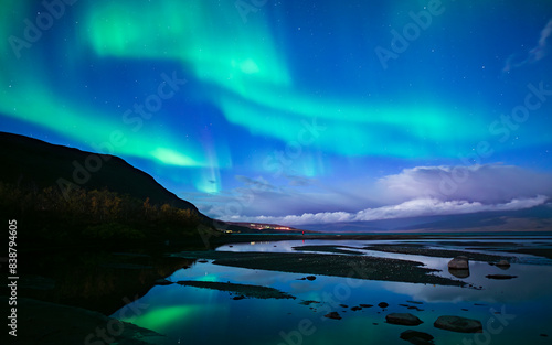 Northern lights dancing over calm lake in Abisko national park in north of Sweden.