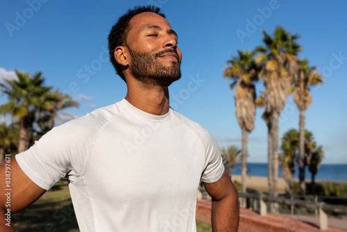 Fototapeta Naklejka Na Ścianę i Meble -  African American man breathing deeply in nature. Black man in sports clothing feeling good after exercising.