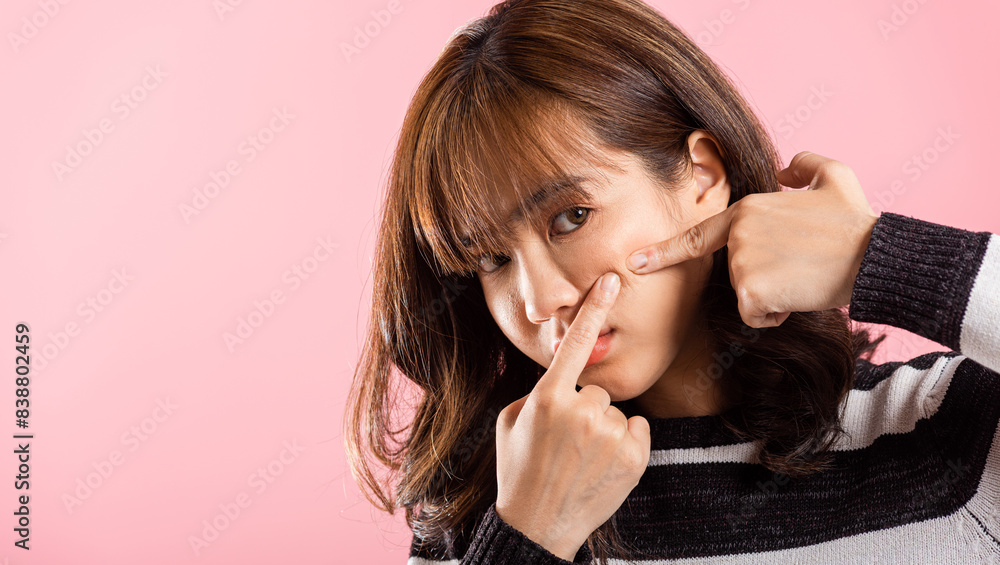 Portrait teenage Asian beautiful young woman having skin problems squeezing pimples acne on her face, studio shot on pink background, with copy space, Thai female acne, beauty care concept Portrait teenage Asian beautiful young woman having skin problems squeezing pimples acne on her face, studio shot on pink background, with copy space, Thai female acne, beauty care concept