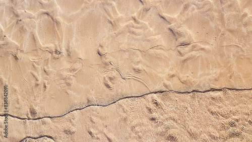 Small waves gently lap the sandy shore in this golden, textured beach pattern.