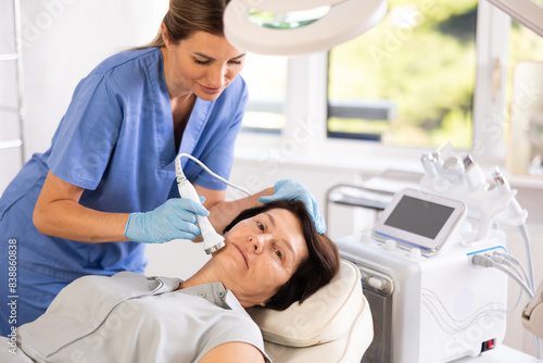 Fotografie Elderly woman undergoing device-driven cosmetic facial treatment using high freq
