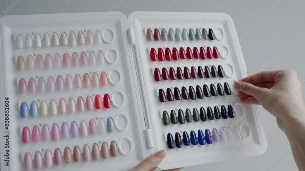 A manicure palette displaying a variety of colorful nail polish samples, showcasing different shades for nail art and beauty treatments. Woman Choosing Nail Polish Color From a Palette In Beauty Salon A manicure palette displaying a variety of colorful nail polish samples, showcasing different shades for nail art and beauty treatments. Woman Choosing Nail Polish Color From a Palette In Beauty Salon