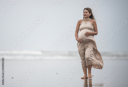 Pregnant mother in third trimester at beach at sunset at cloudy day photo