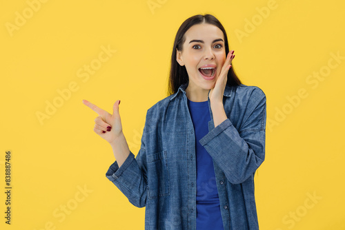 Foto Stunning female brunette with shocked facial expression looking pointing on copy space