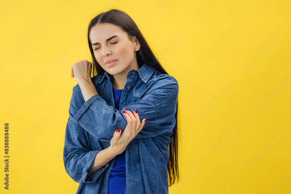 Sick casually dressed caucasian woman suffering from inflammation in hand or arthritis in yellow studio. Sick casually dressed caucasian woman suffering from inflammation in hand or arthritis in yellow studio.