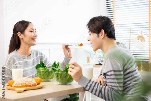 Asian couple  drinking milk and eating vegetable  breakfast  in kitchen at home .