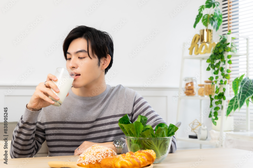 Asian man drinking milk and eating vegetable breakfast in kitchen at home . Asian man drinking milk and eating vegetable breakfast in kitchen at home .