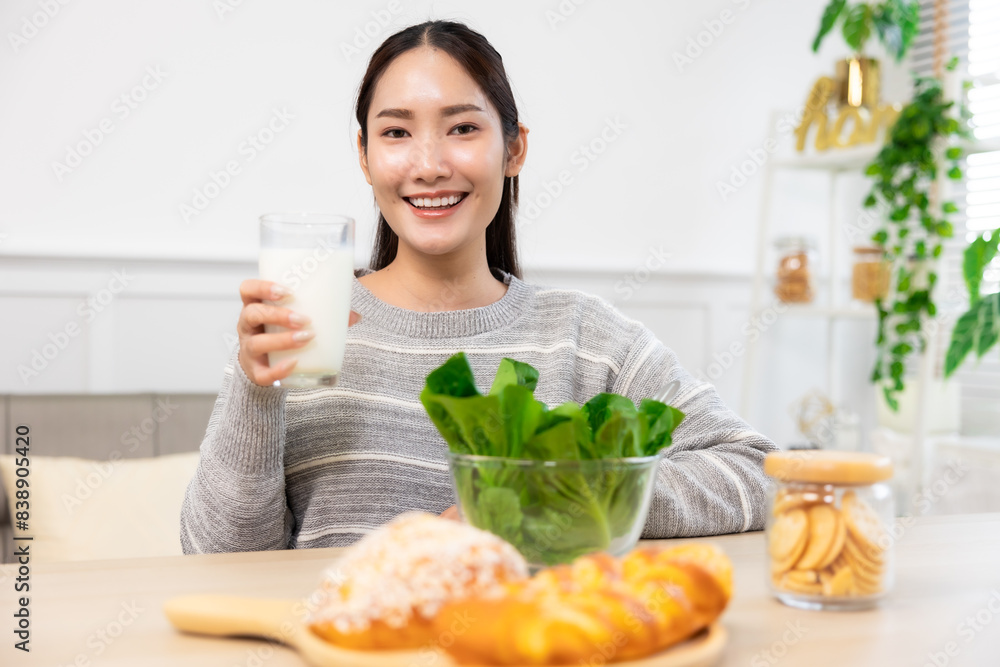Asian woman drinking milk and eating vegetable breakfast in kitchen at home . Asian woman drinking milk and eating vegetable breakfast in kitchen at home .