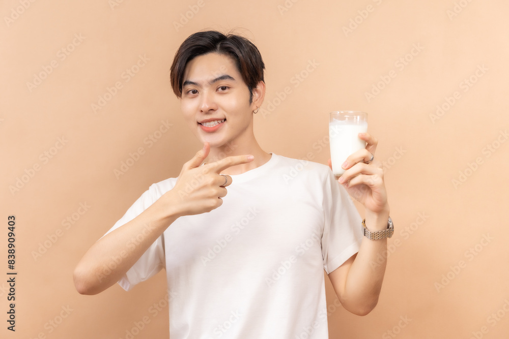 A happy asian people in white shirts, holding glasses of milk and a bowl of salad, against a beige background. A happy asian people in white shirts, holding glasses of milk and a bowl of salad, against a beige background.
