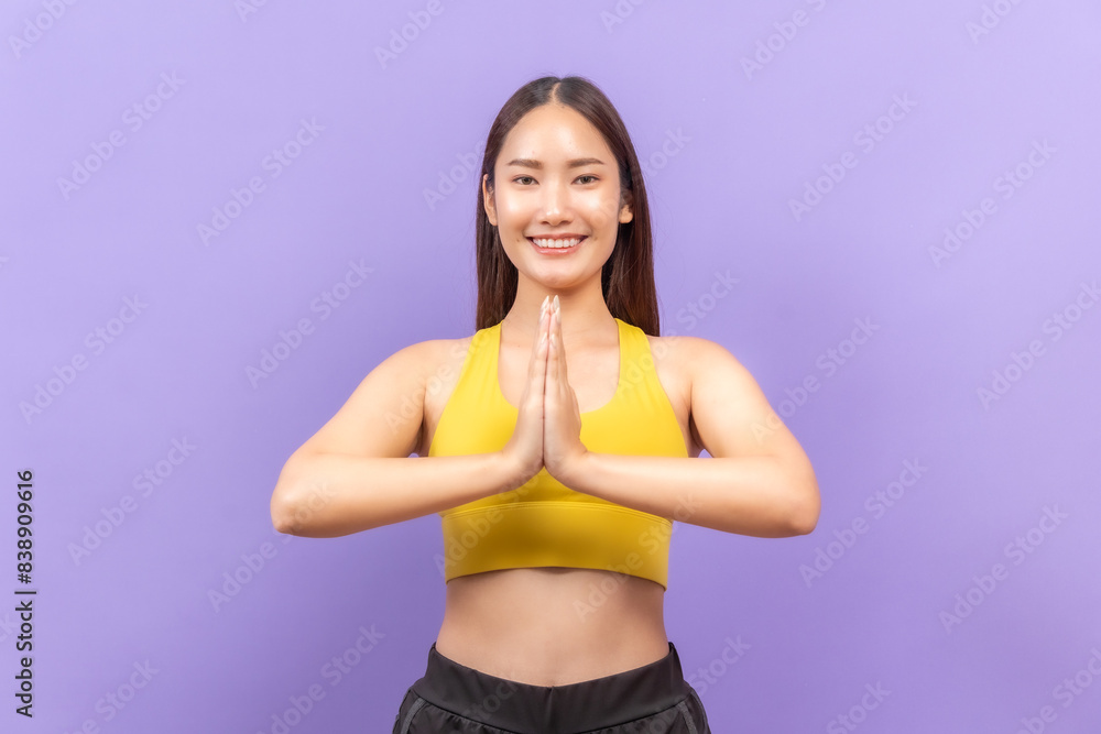 Smiling asian woman in yellow sportswear performing a fitness stretch, set against a bold purple background. Smiling asian woman in yellow sportswear performing a fitness stretch, set against a bold purple background.