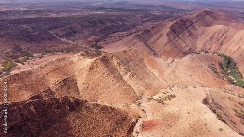 Aerial panning shot of the Flinders Ranges and Aroona Dam in South Australia. A scenic view of the Outback with its iconic red dirt, hills, and trees. photo